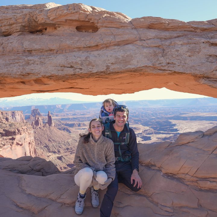 Shir with her husband and baby under Mesa Arch