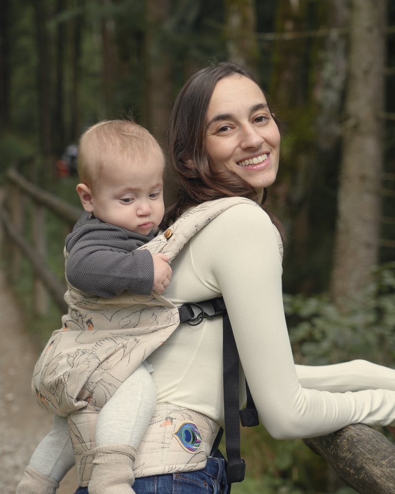 Shir smiling on a forest trail with her baby on her back